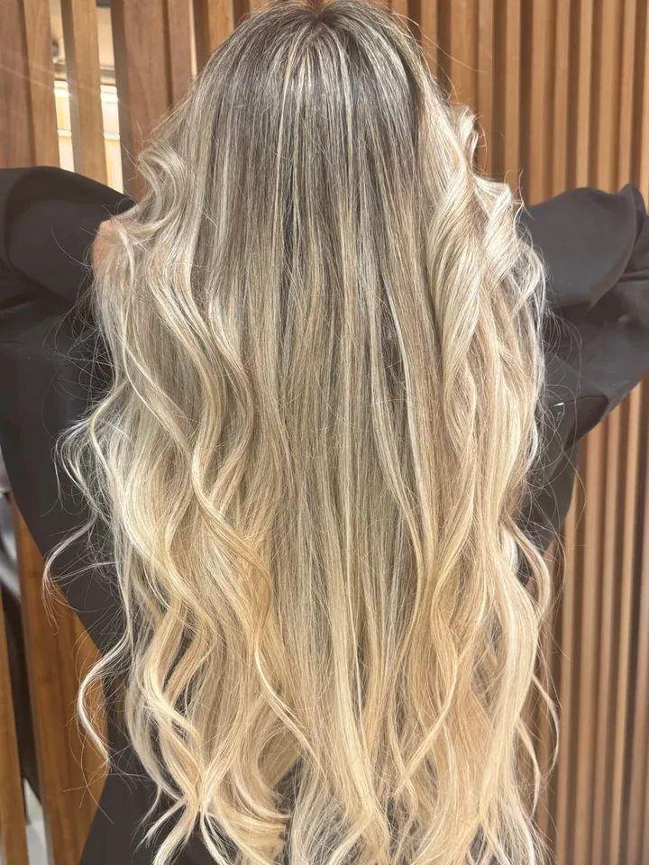 Loiro longo com raiz esfumada e ondas, visto de costas no salão